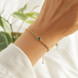 Bracelet souple plaqué or pendentif goutte verte porté par une femme