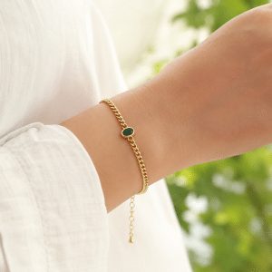 Bracelet souple plaqué or pendentif ovale vert porté par une femme